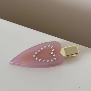 Détail de la pince à cheveux cœur en résine rose avec strass brillants et métal doré