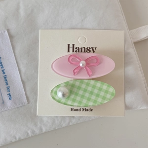 Détail de pinces à cheveux en acrylique rose à nœud et à carreaux verts sur carte