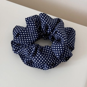 Detail of navy blue fabric hair scrunchie with white polka dots and elastic texture