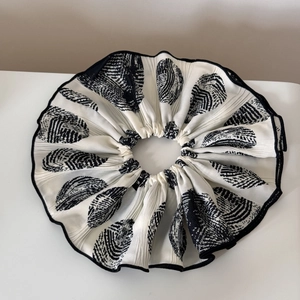 Macro detail of pleated scrunchie showing black and white shell pattern and fine texture