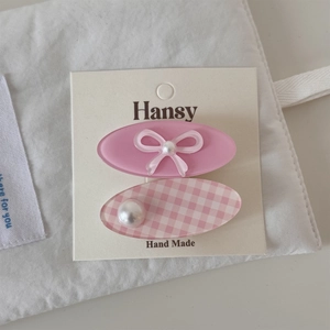 Détail de barrettes à fleurs roses avec perles et nœuds sur carte de présentation