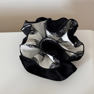 Detail view of large pleated scrunchie with black and white tropical floral pattern print