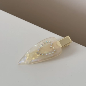 Vue détaillée de l'incrustation de strass en cœur sur pince à cheveux en acétate jaune