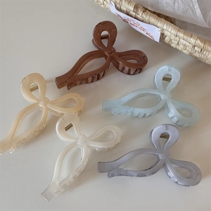 Detail view of five marble texture ribbon bow hair claws in jelly colors with gold springs