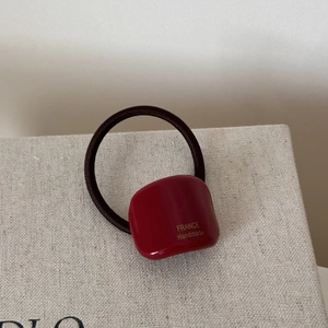Macro shot of dark burgundy resin hair tie detail with gold France Handmade lettering