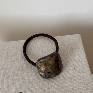 Detailed macro view of acetate hair tie with golden lettering and tortoiseshell texture