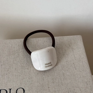 Macro detail of white acetate hair tie accessory with FRANCE Handmade gold inscription