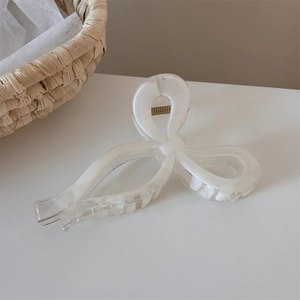 Detailed view of cream ribbon bow hair claw clip with golden metal spring structure