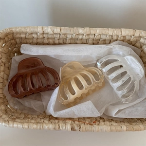 Trois pinces à cheveux en acrylique marron, beige et blanc givré dans un panier en paille