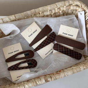 Brown plaid and solid fabric hair clips set on display card in a woven basket