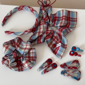 Detail view of red and blue tartan fabric accessory set including hair clips and scrunchies