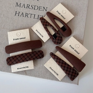 Detail view of brown plaid and solid fabric hair clips set on a cream card