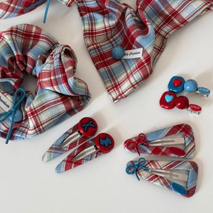 Detail of red and blue plaid bow hair clips and scrunchie set with heart button accents
