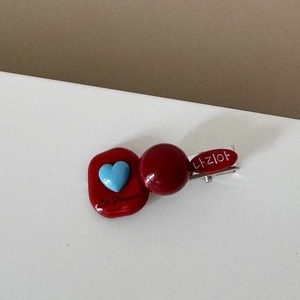 Detail of red and blue checkered hair clip with heart button and heart button accents