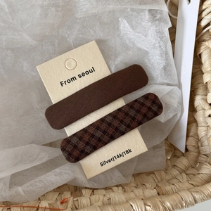 Close-up of brown plaid and solid fabric hair clips set on a beige display card