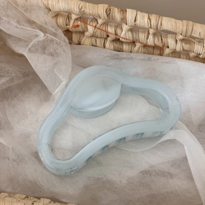 Détail d'une pince à cheveux bleu clair translucide avec texture ondulée sur filet blanc