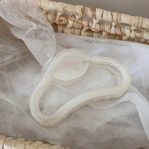 Détail d'une grande pince à cheveux crème au design ondulé sur fond de panier tressé