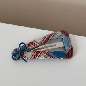 Detailed shot of red blue plaid fabric hair clip with a bow and stars button detail