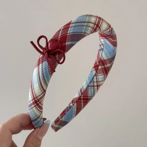 Detail of red and blue plaid fabric headband with a sweet bow and heart button accent
