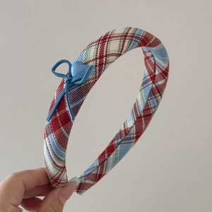 Detail of red and blue plaid fabric headband with blue bow and heart button