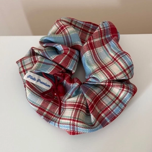 Detail of red and blue plaid scrunchie with heart pendant and Plate Premium label
