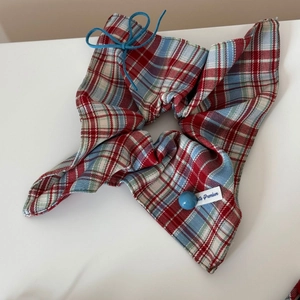 Detail of red and blue plaid bow hair clip featuring a blue bead and heart button