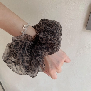 Detail of a large leopard print mesh hair scrunchie with voluminous chiffon fabric on a wrist