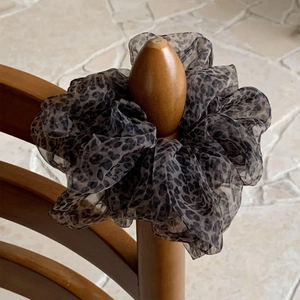 Detail showing the sheer leopard print mesh fabric texture of a brown scrunchie