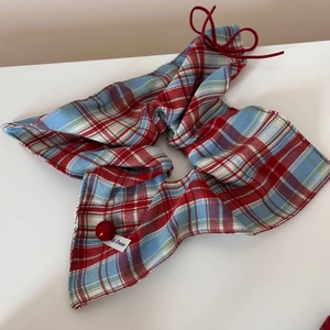 Close-up of red and blue plaid bow hair clip with decorative bead and premium woven label