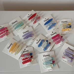 Détail de barrettes à cheveux colorées avec motifs à carreaux et étoiles sur cartes blanches