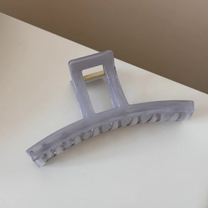 Close-up of translucent grey-purple large claw clip with square cutout and gold spring