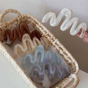 Close-up of wave-shaped resin hair claws in Morandi colors inside a woven basket