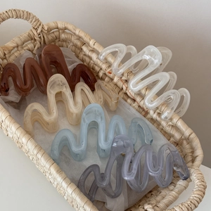 Elegant large wavy hair clips in assorted translucent colors displayed in a woven basket