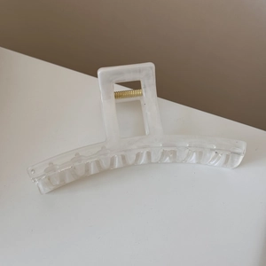 Detail view of a white marble texture hair claw clip with a strong gold metal spring