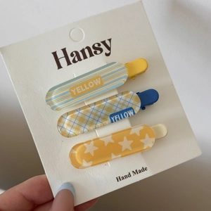 Détail d'un lot de trois barrettes colorées à carreaux et rayures sur carte blanche