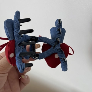 Close-up of denim fabric hair claw clip with red polka dot hearts and spring detail