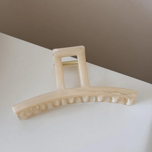 Close-up of translucent jelly-style hair claw clip with golden metal spring mechanism