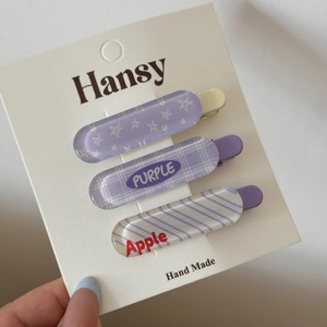 Détail de trois barrettes à cheveux violettes avec motifs à carreaux et étoiles sur carte