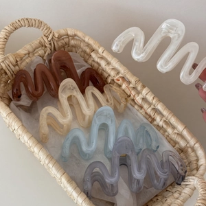 Close-up of wavy resin hair claws in tortoiseshell and pastel colors on white tissue