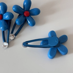 Detail view of blue flower hair clips with red bead centers and sparkling crystal accents