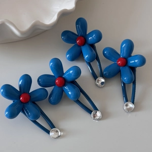 Close-up of blue flower hair clips with red bead centers and sparkling rhinestones