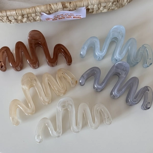 Detail view of wave-shaped resin hair claws in five colors including blue and brown