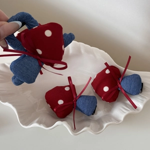 Handmade red polka dot mushroom hair clips and ties with bows in a white shell dish