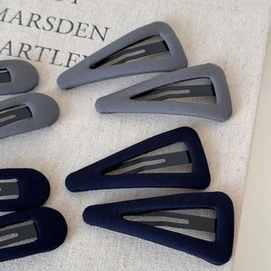 Detail of fabric geometric triangle hair clips in grey and navy with twill texture