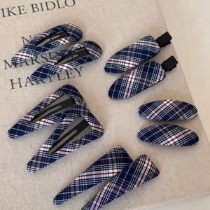 Detail of navy blue plaid fabric hair clips set on rustic linen background