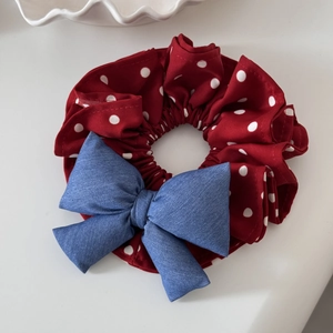 Macro shot of red polka dot scrunchie with blue denim bow detail on white surface