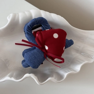 Detail of red polka dot heart and ribbon bow on blue denim fabric claw hair clip