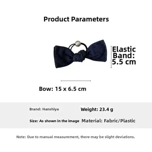 Detail of blue denim bow hair tie featuring a white faux pearl on black elastic band
