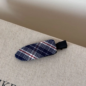 Detailed macro view of navy blue plaid fabric hair clip with a black matte finish clip