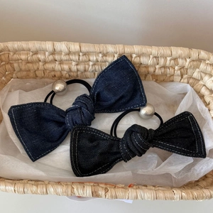 Close-up of denim bow scrunchies with white contrast stitching and silver bead details
